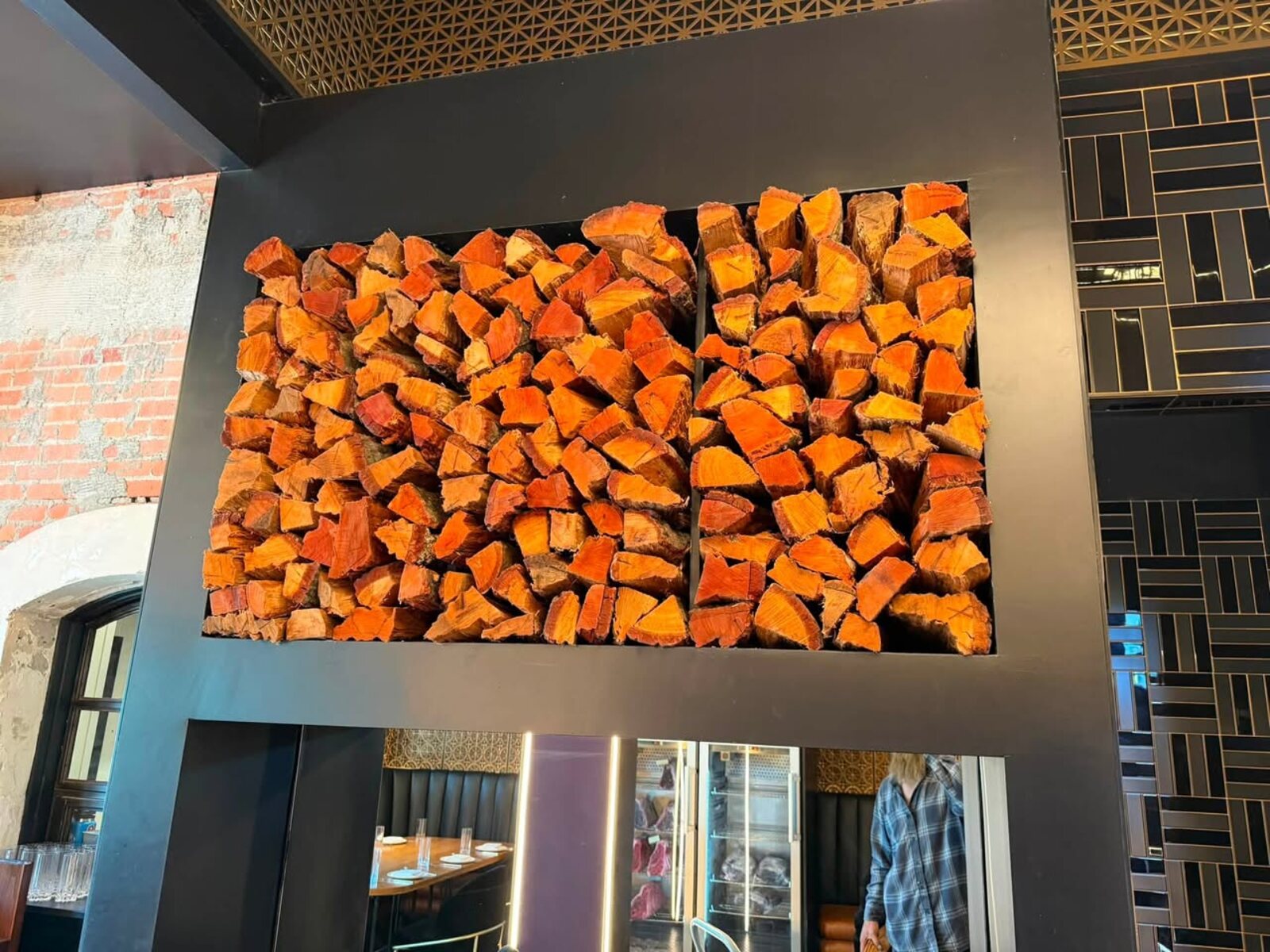 Split oak stacked in a steel feature wall inside a Santa Barbara steakhouse dining room