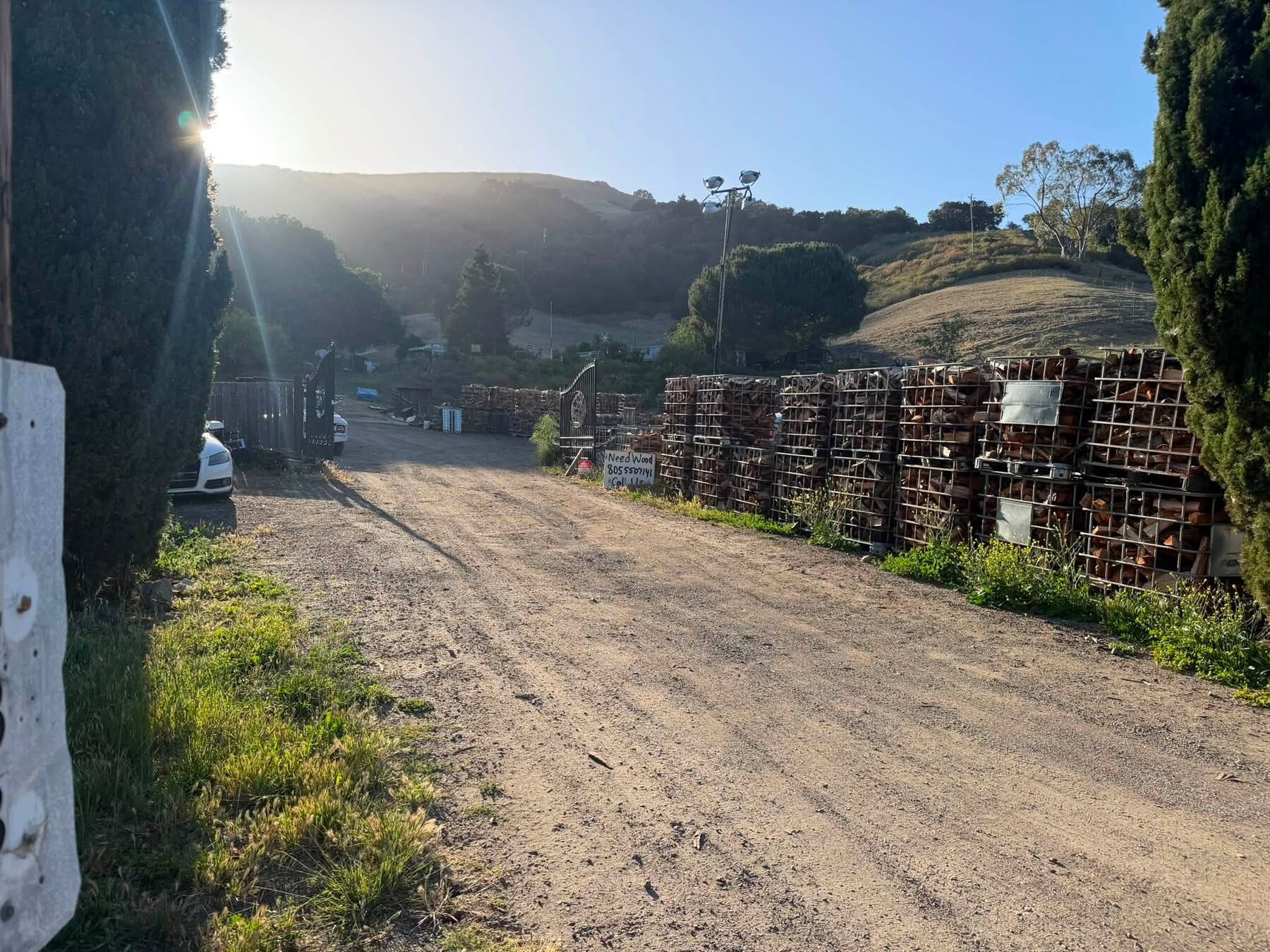 Baskets of split oak lined up along the drive at the 805 Red Oak yard, with a sign reading Need Wood, call 805-550-7141