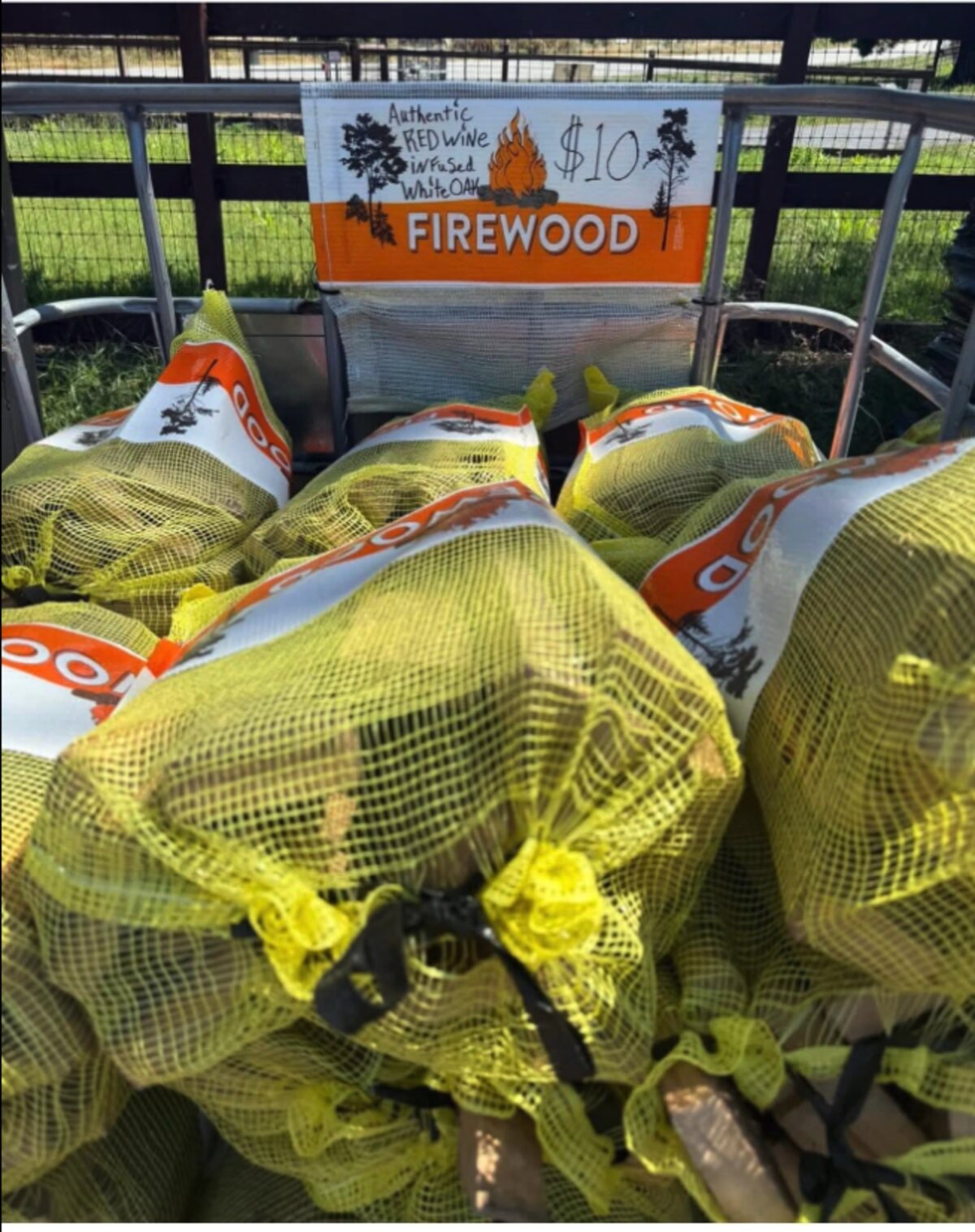 Bags of authentic red wine infused white oak firewood at the 805 Red Oak self-serve stand, marked $10